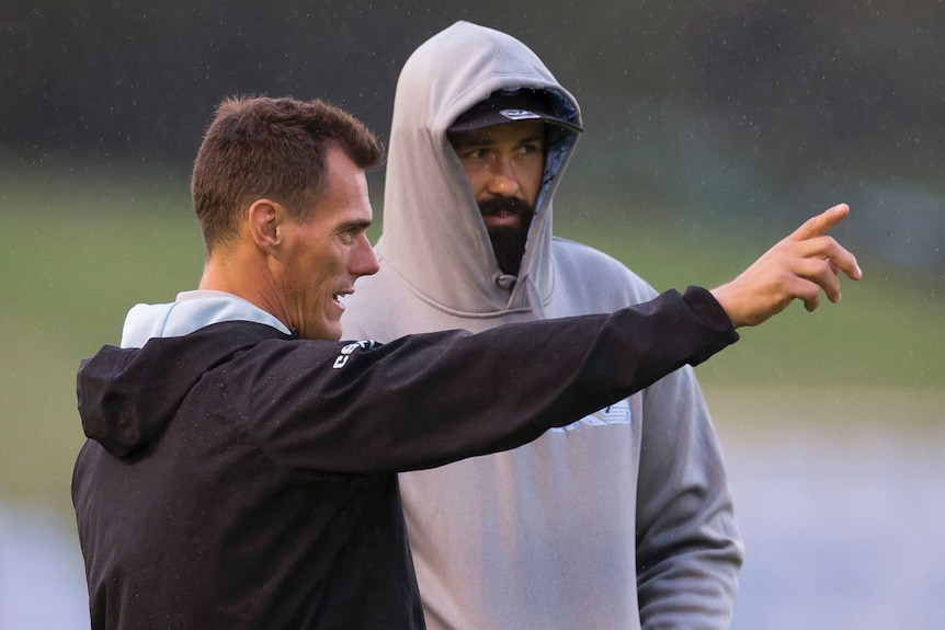 A Cronulla NRL coach talks to one of his players as he points with his right hand.