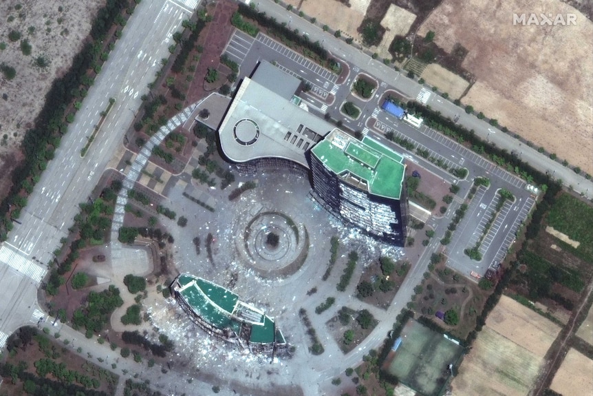 A satellite image shows a demolished building with shattered glass strewn across concrete