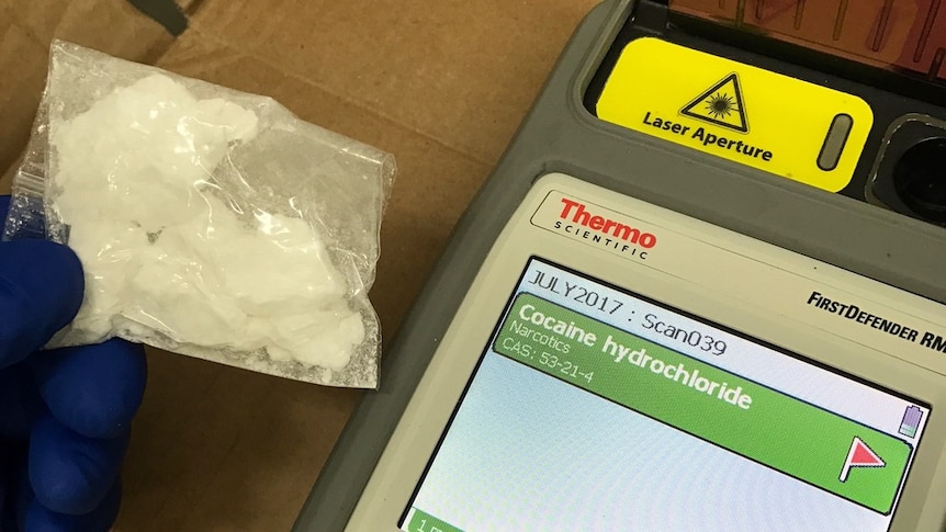 A bag of white powder next to a screen which says 'cocaine'