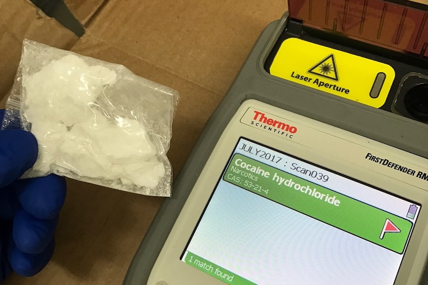 A bag of white powder next to a screen which says 'cocaine'