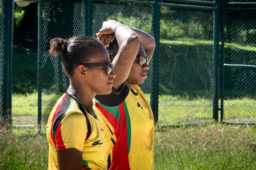 Two women in yellow t-shirts stand next to each other.