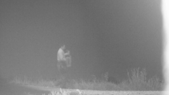 A man carries a small boy near the US-Mexico border in this grainy black and white photo.