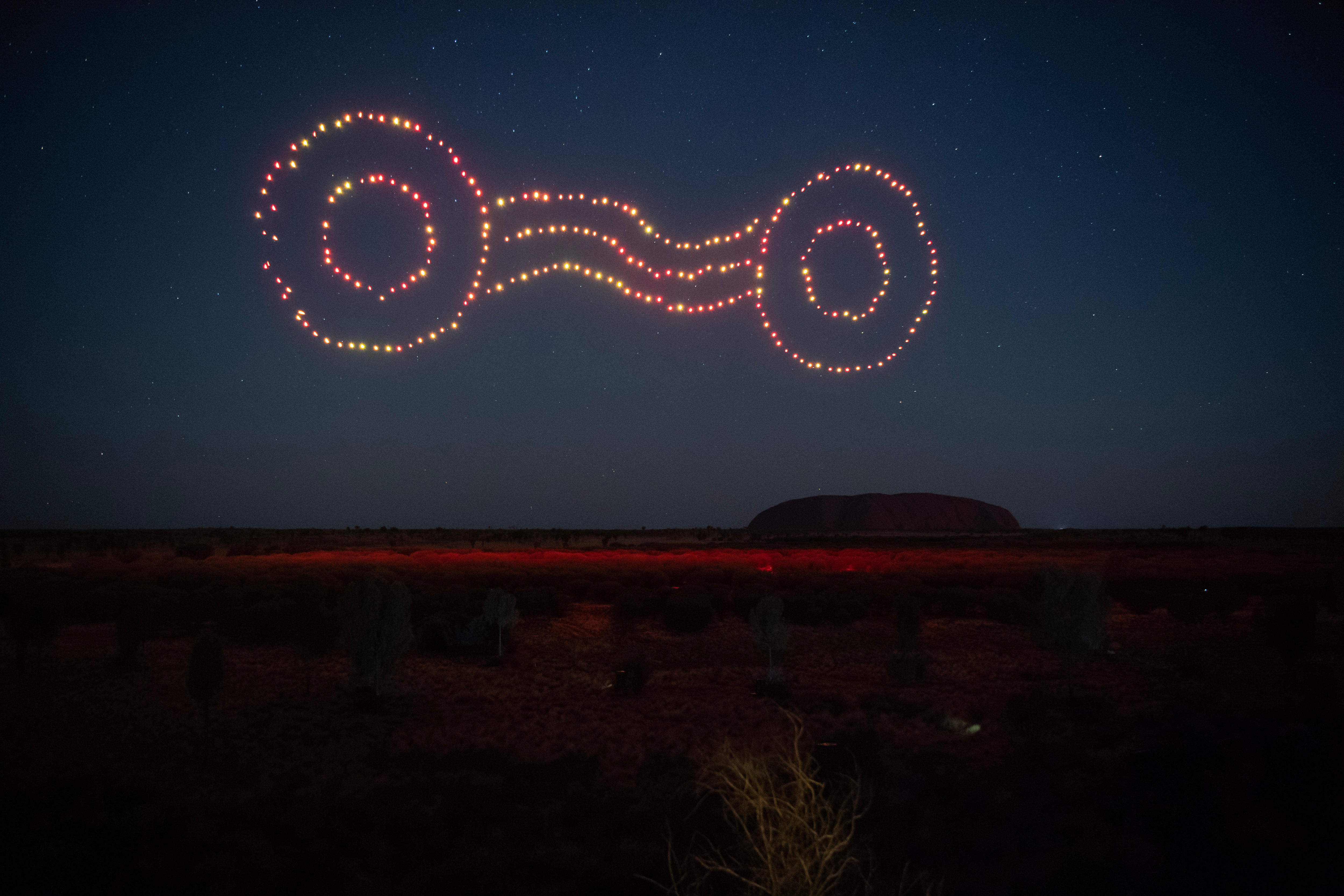 Indigenous songline symbol in coloured lights in the dark ink blue sky above Uluru in Northern Territory
