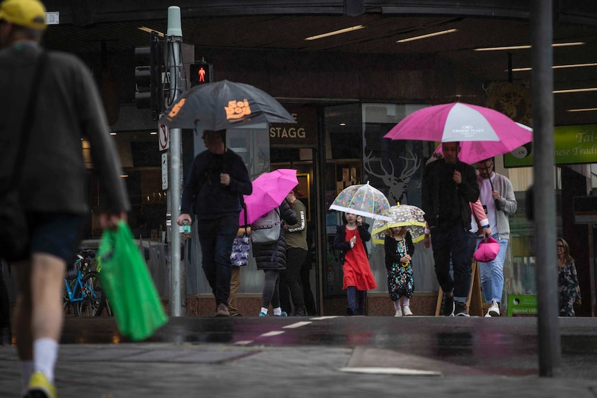 People walk on a city street holding umbrellas over their heads