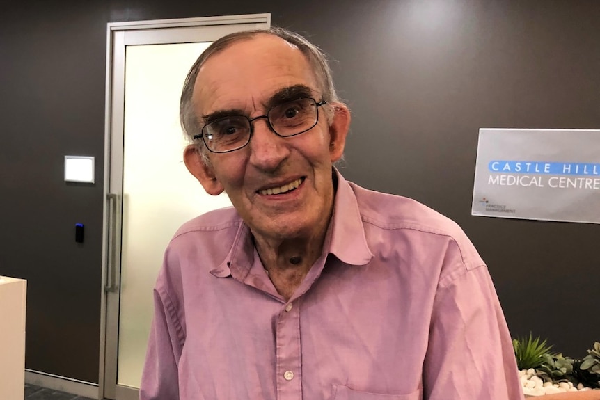 An elderly man smiles at the camera.