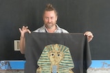Mikey Webb holdling his cross-stitch of Tutankhamen