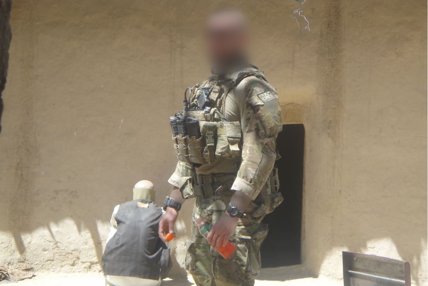 An Australian solder stands in front of an Afghanistan building.