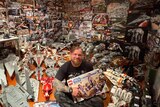 A smiling, tattooed man in a room jam packed with Lego Star Wars toys.