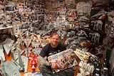 A smiling, tattooed man in a room jam packed with Lego Star Wars toys.