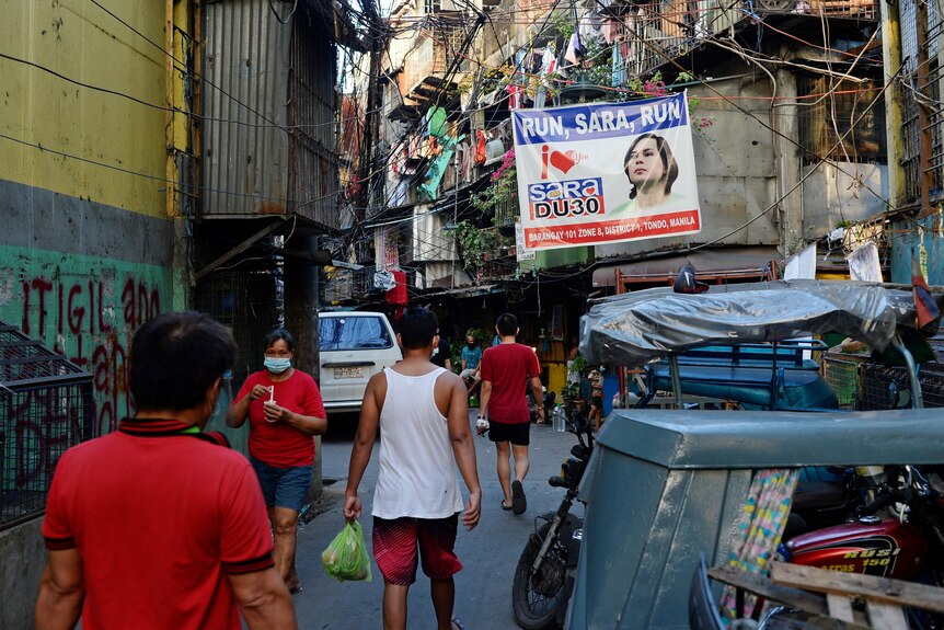 A poster reading 'Run, Sara, Run' on a building in a Manila street
