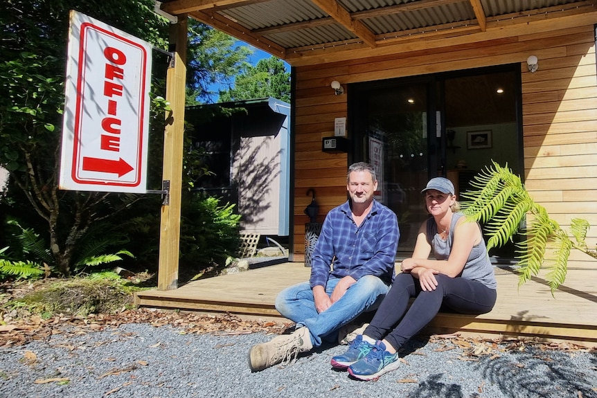 Clayton McCuddon and Ali Collier sit on the veranda of a small wooden building