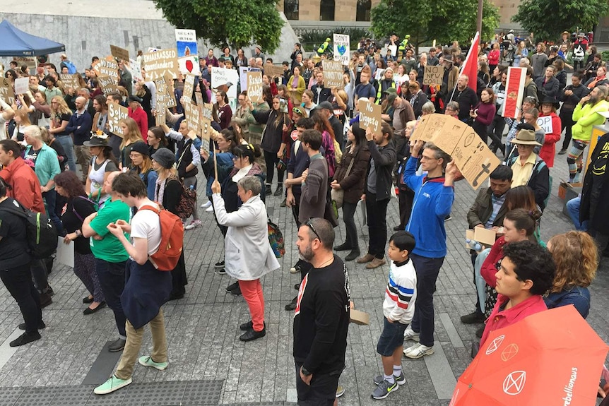 Brisbane university students hold signs and walk through the city