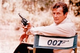Roger Moore on set holding a gun, playing James Bond in 1972.