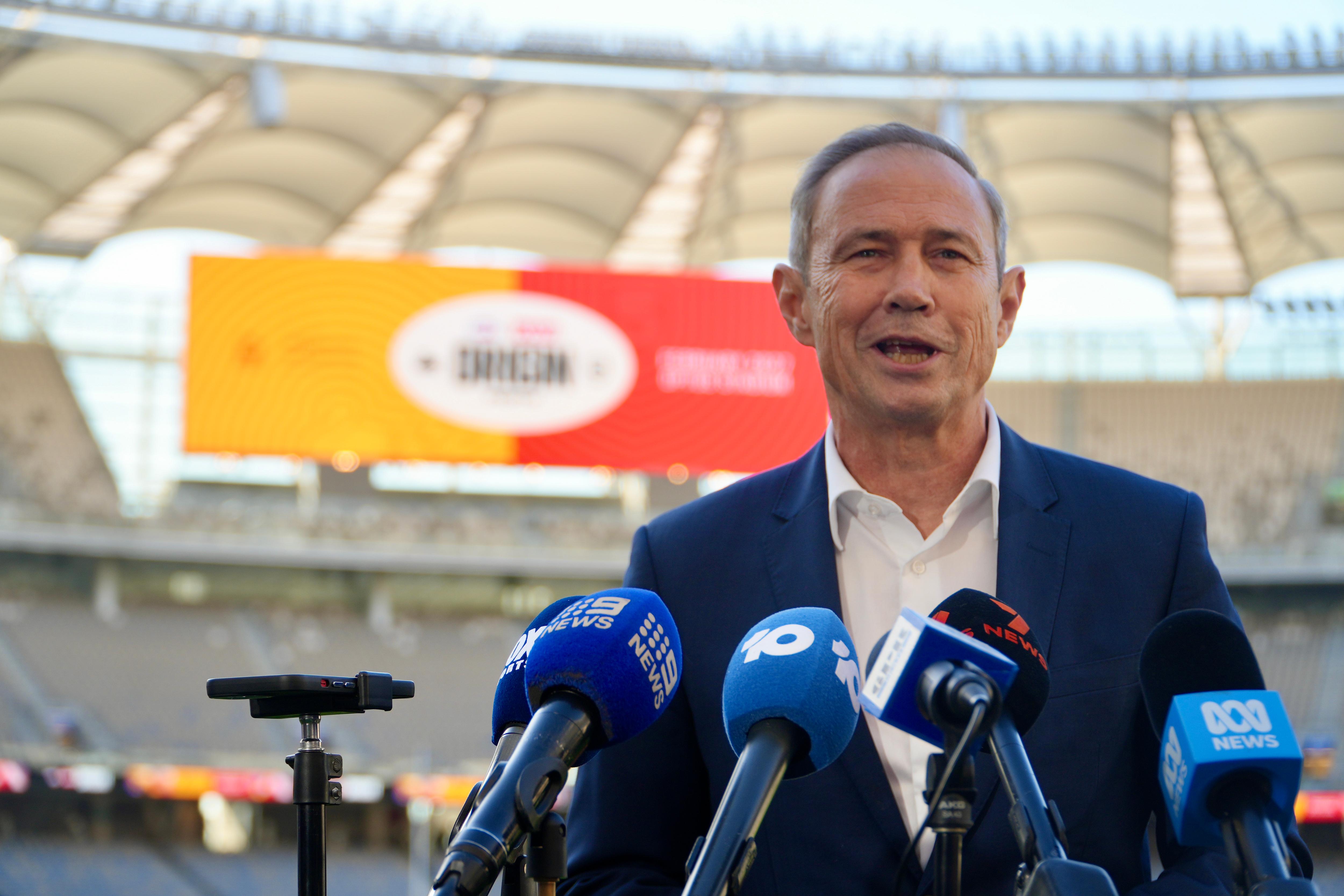 Roger Cook speaks in front of microphones at Optus Stadium. 