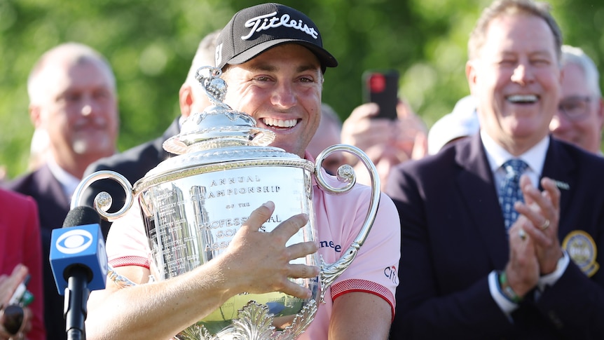 Justin Thomas smiles as he holds the Wanamake Trophy tight to his chest