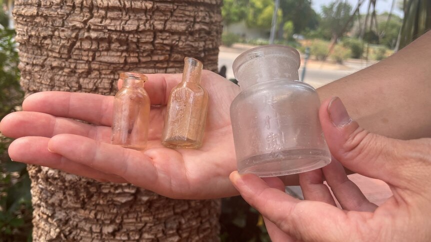 Hands holding three tiny bottles