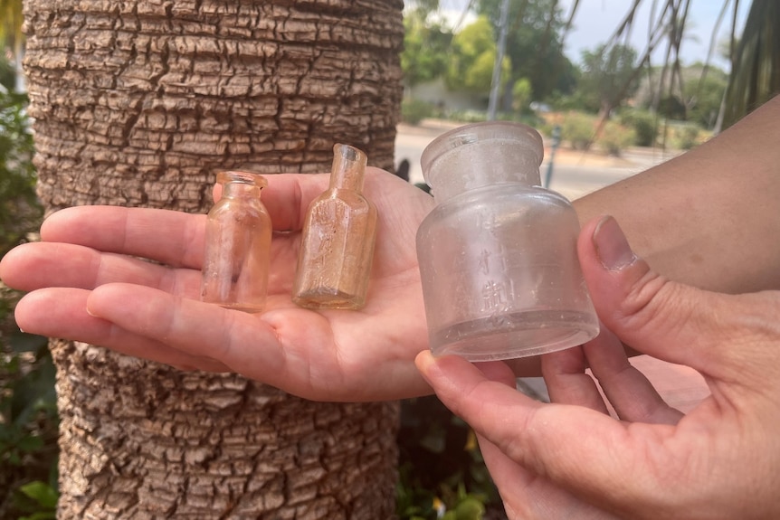 Hands holding three tiny bottles