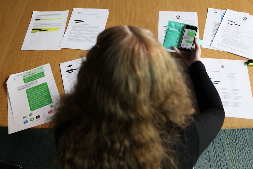 A woman, seen from above and unidentifiable, poring over documents on a table.