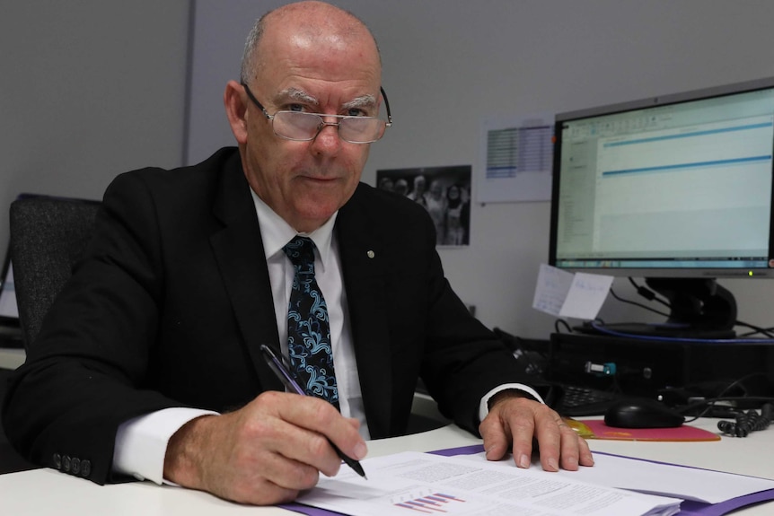 ACT Victims of Crime Commissioner John Hinchey sits at his desk.