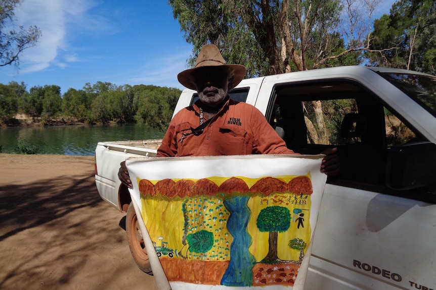 Senior Garawa man Jack Green stands by the McArthur River with a painting depicting how he sees the consultation process
