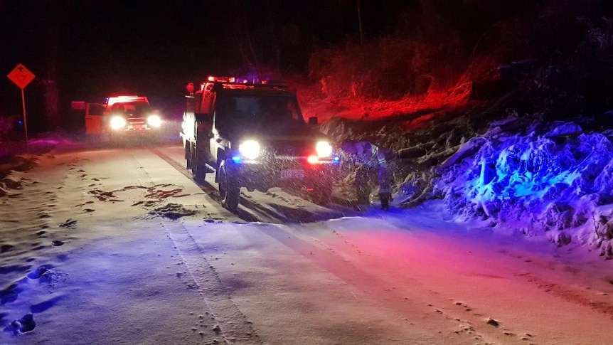 Rescue vehicles with their lights on at night in the snow.