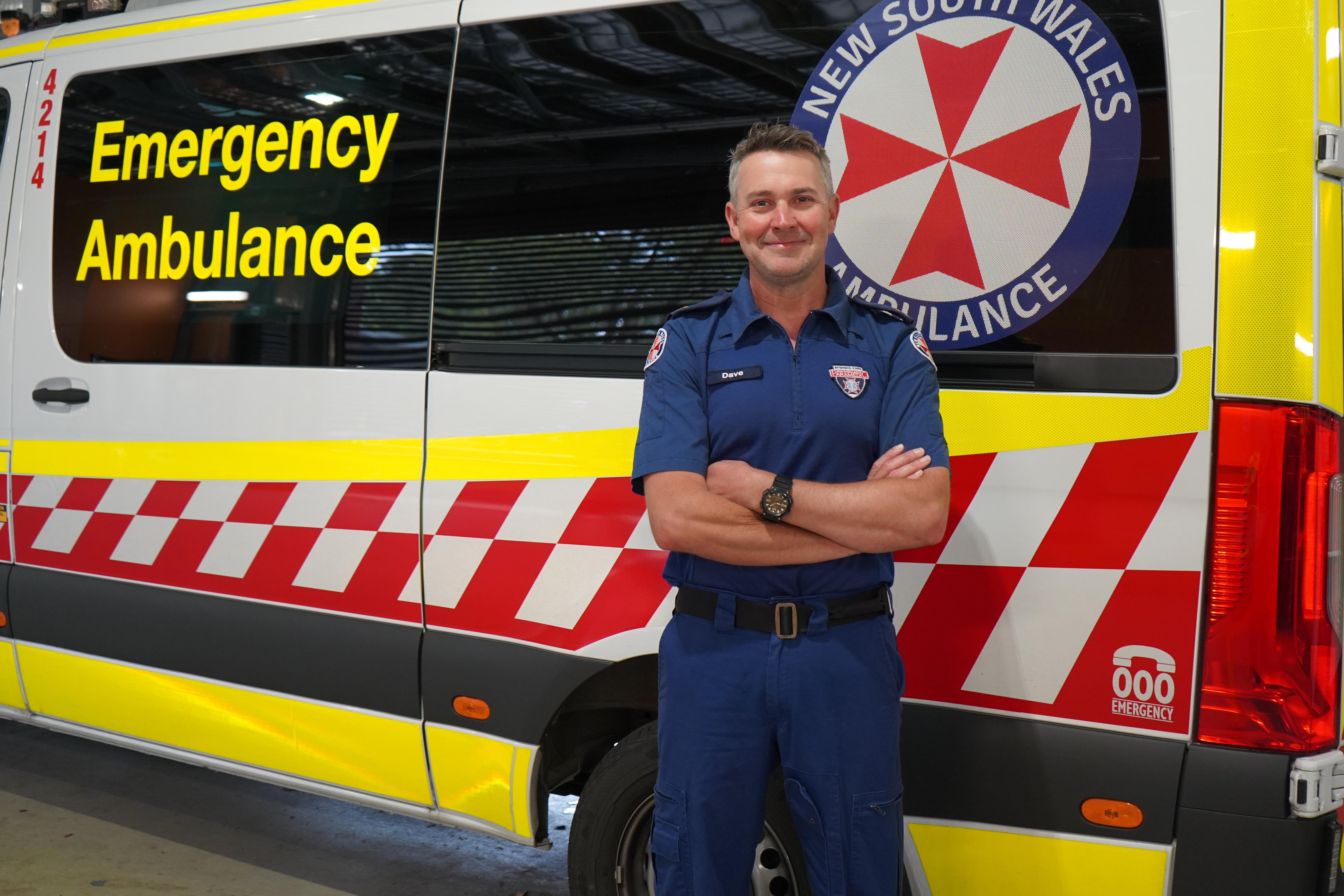 Un feliz paramédico se encuentra frente a la ambulancia de Nueva Gales del Sur.