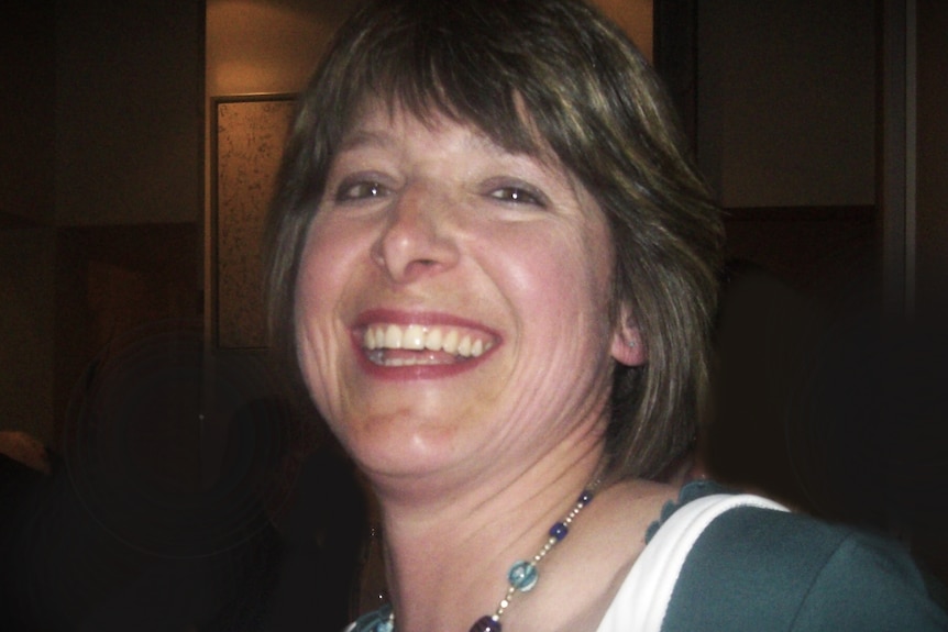 A middle-aged woman smiles at the camera.