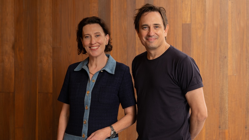 Virginia Trioli, a woman in her 50s, and Trent Dalton, a man in his 40s, smile together, Dalton with his arms behind his back.