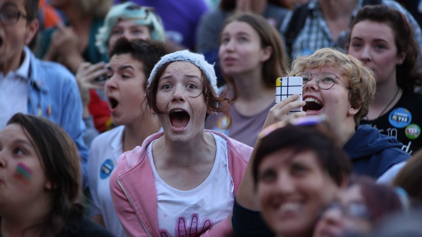 A girl screams for joy and people cry at a gathering in the centre of perth