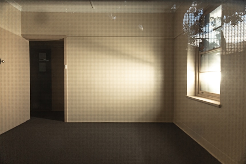 An empty room with an open door and light shining through a window on the right