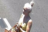 CCTV still of Toyah Coringley with hair up walking across the road carrying a basket.