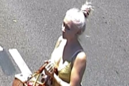 CCTV still of Toyah Coringley with hair up walking across the road carrying a basket.