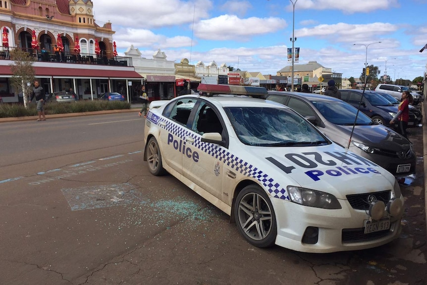 A police vehicle with its windows smashed and crushed sits parked on the side of Hannan Street in Kalgoorlie.