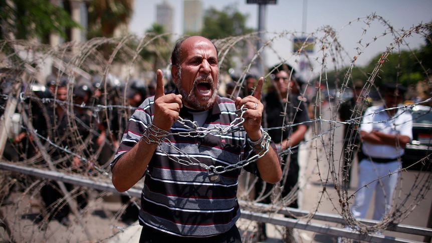 An Egyptian protester shouts in front of police outside the Supreme Constitutional Court.