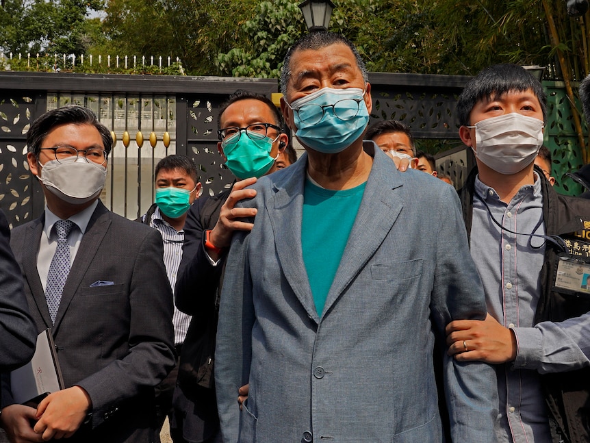 Hong Kong media tycoon Jimmy Lai, center, who founded local newspaper Apple Daily, is arrested by police officers at his home.