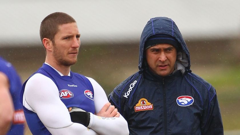 Matthew Boyd and assistant coach Wayne Schwass talk tactics in the rain at training.