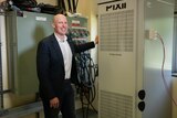 Lachlan Blackhall stands in front of a battery storage unit