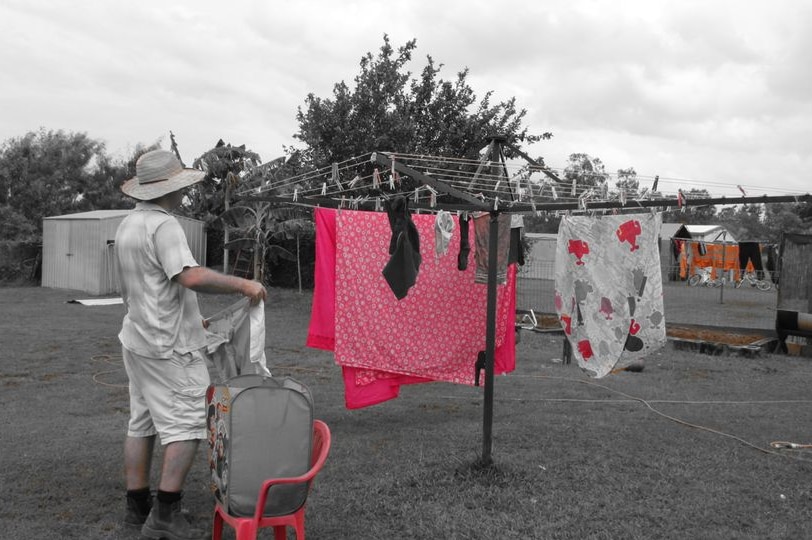 A man hanging out washing on a rotary clothesline for a story about how often you should change your sheets.