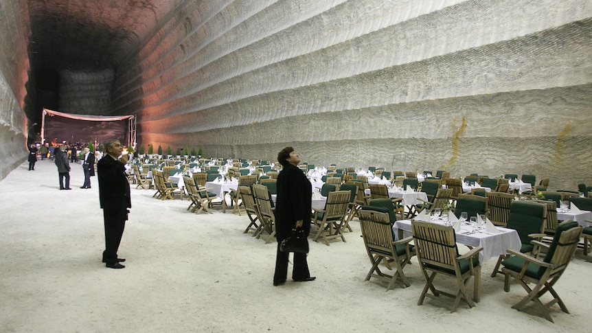 People in suits inside a salt mine with several chairs and tables set up