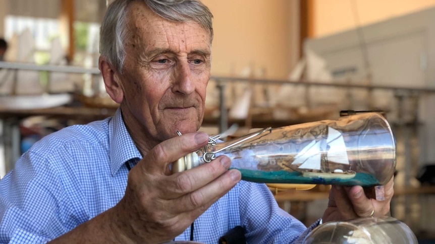 Michael Stoddart holds a ship-in-a-bottle from his collection.
