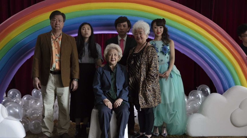 A Chinese family poses for a portrait in front of a rainbow