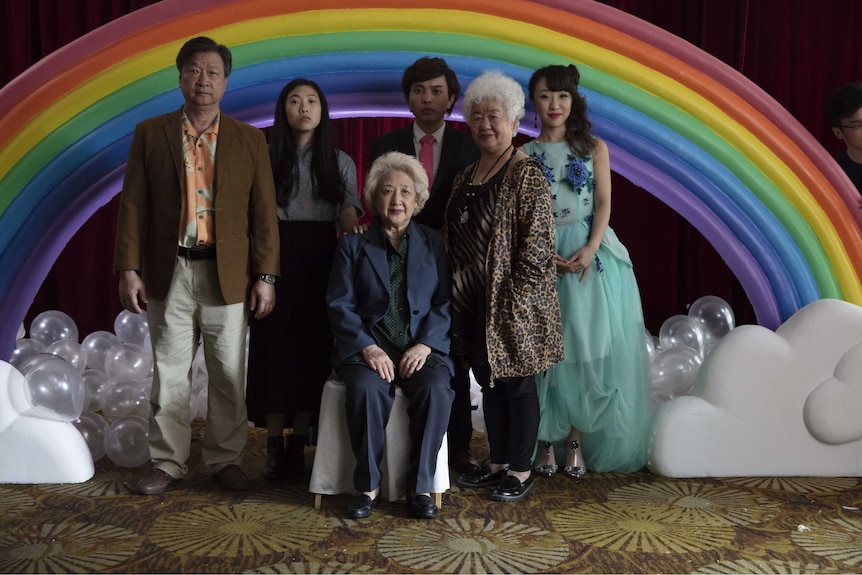 A Chinese family poses for a portrait in front of a rainbow