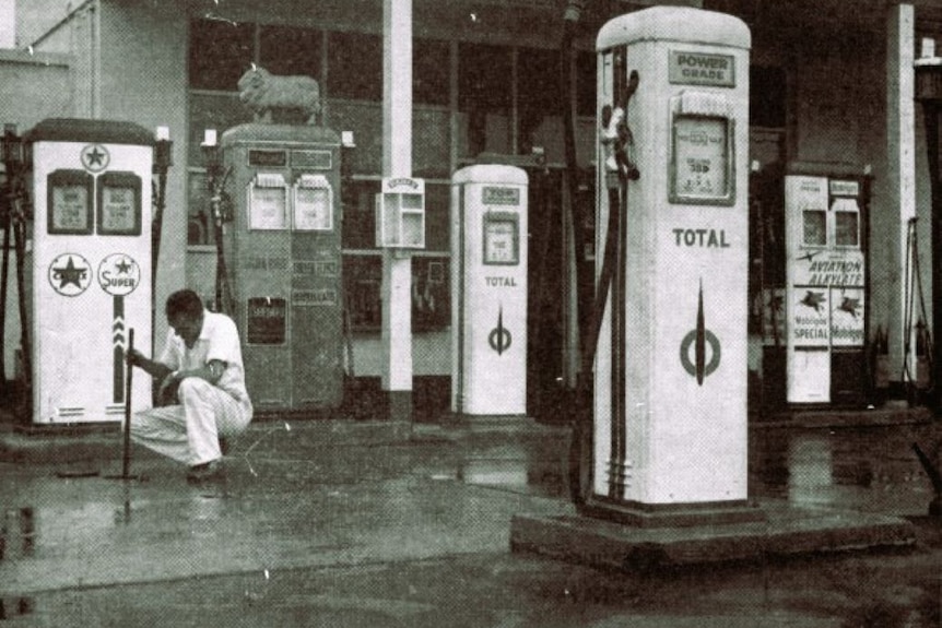 A black and white photo of multi brand fuel pumps standing beside each other