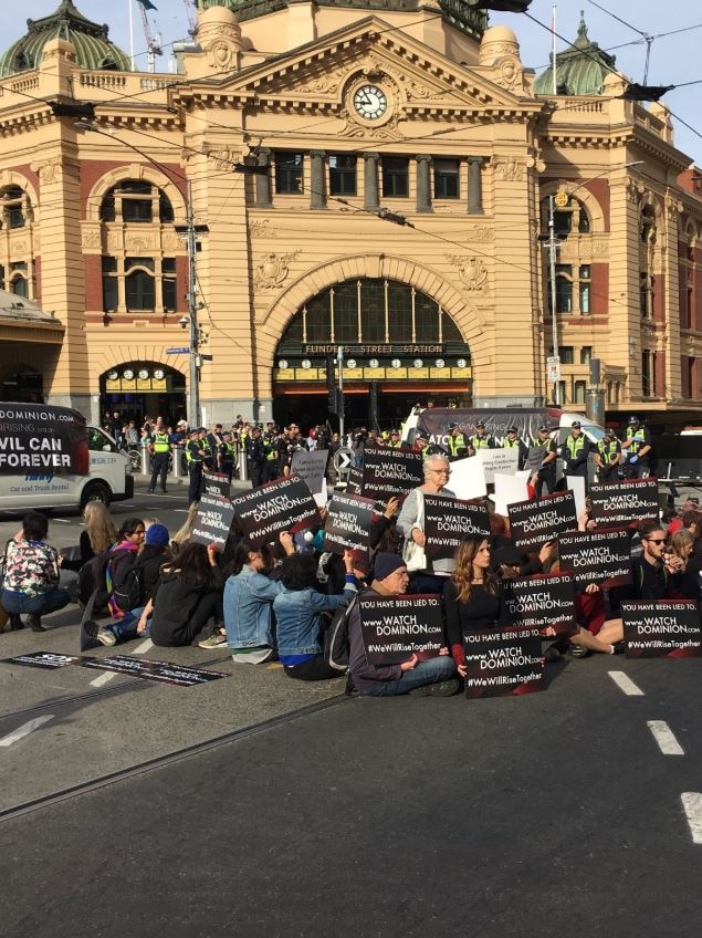 Animal rights protestors sit in centre of Flinders Street intersection.