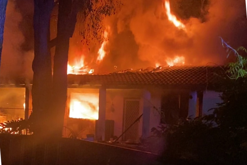 A house fully engulfed in flames at night