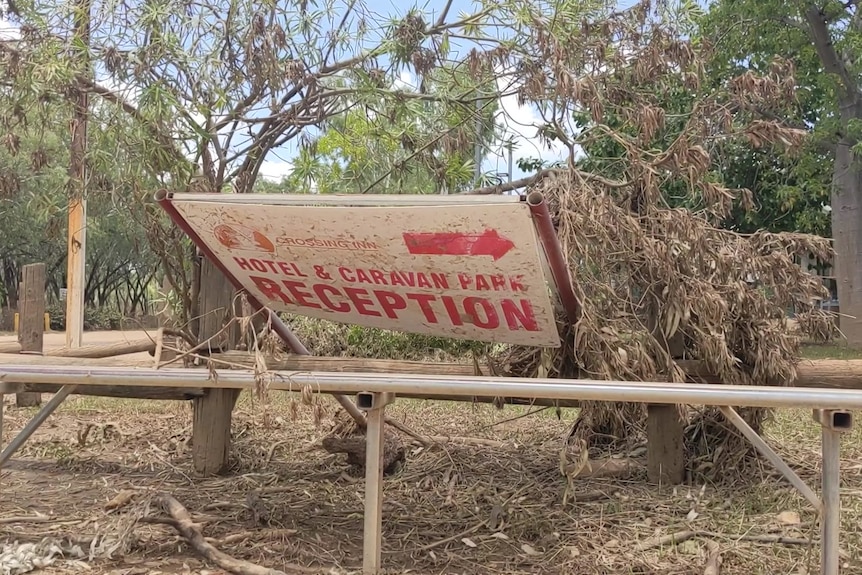 An overturned sign for a motel and caravan park reception