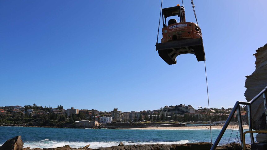 Excavator is lifted down to rocks at Coogee Beach