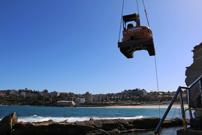 Excavator is lifted down to rocks at Coogee Beach