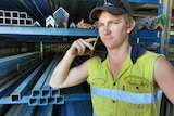 A young man stands in front of steel with a mobile phone to his ear