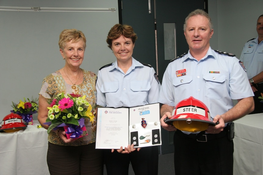 A female fire officer in the centre, flanked by her mother and a senior fire officer